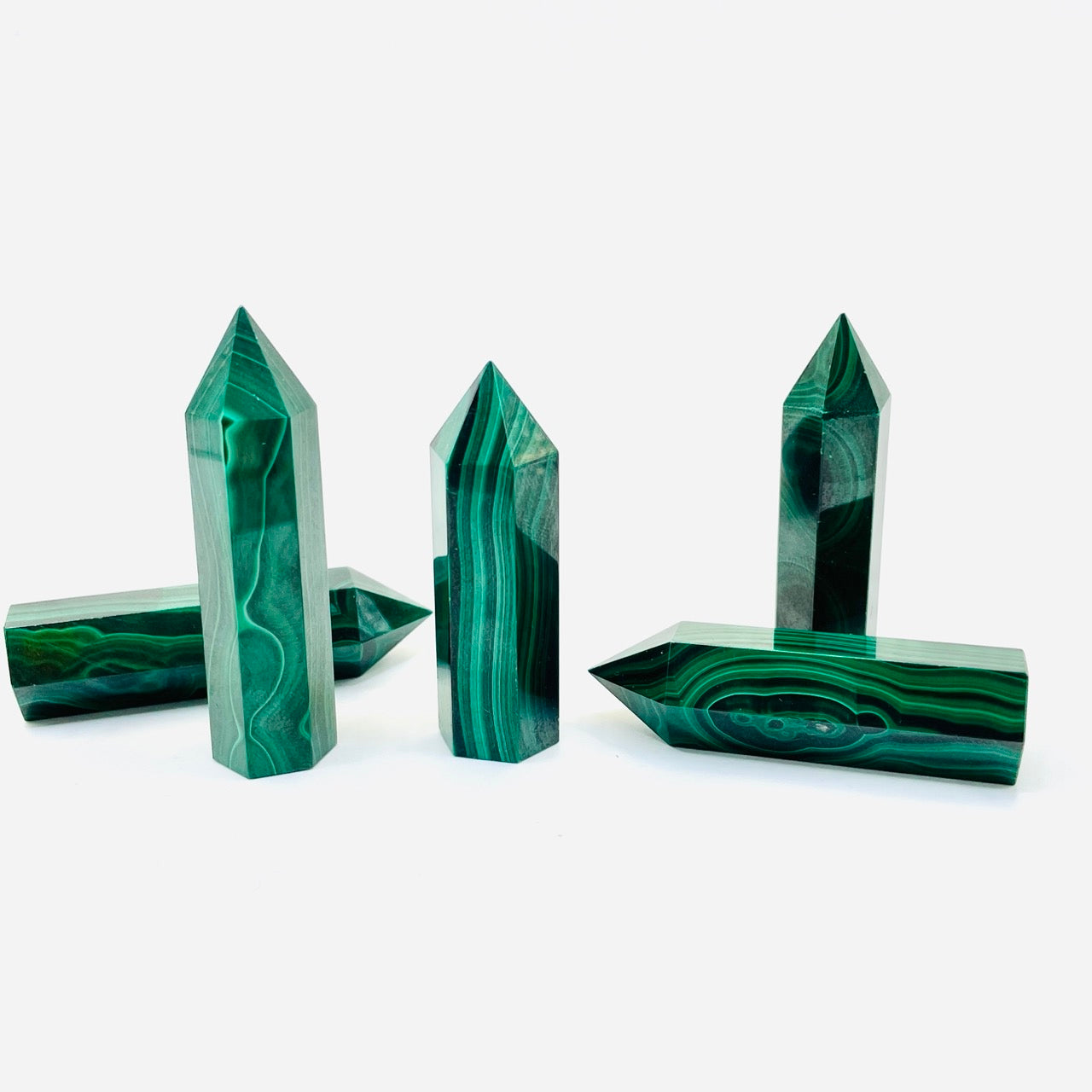 A collection of malachite crystal points displayed on a white surface.