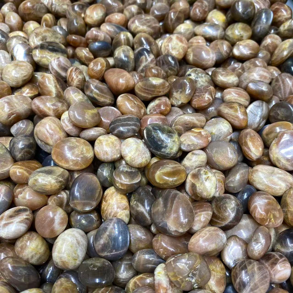 A dense pile of polished, smooth river stones in earthy brown, tan, beige, and gray tones with natural marbled patterns.